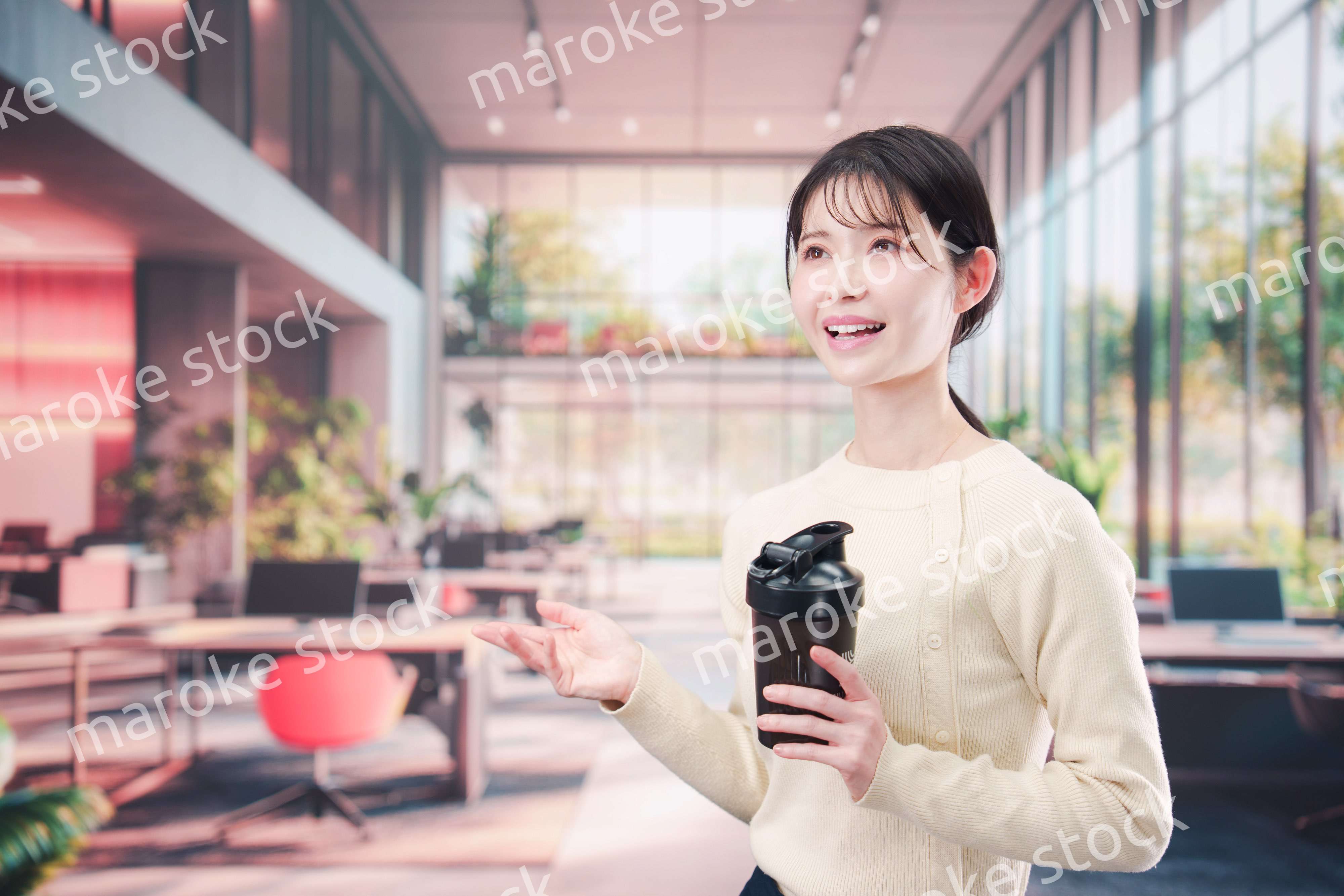 オフィスでマイボトルを持ち歩く若い女性