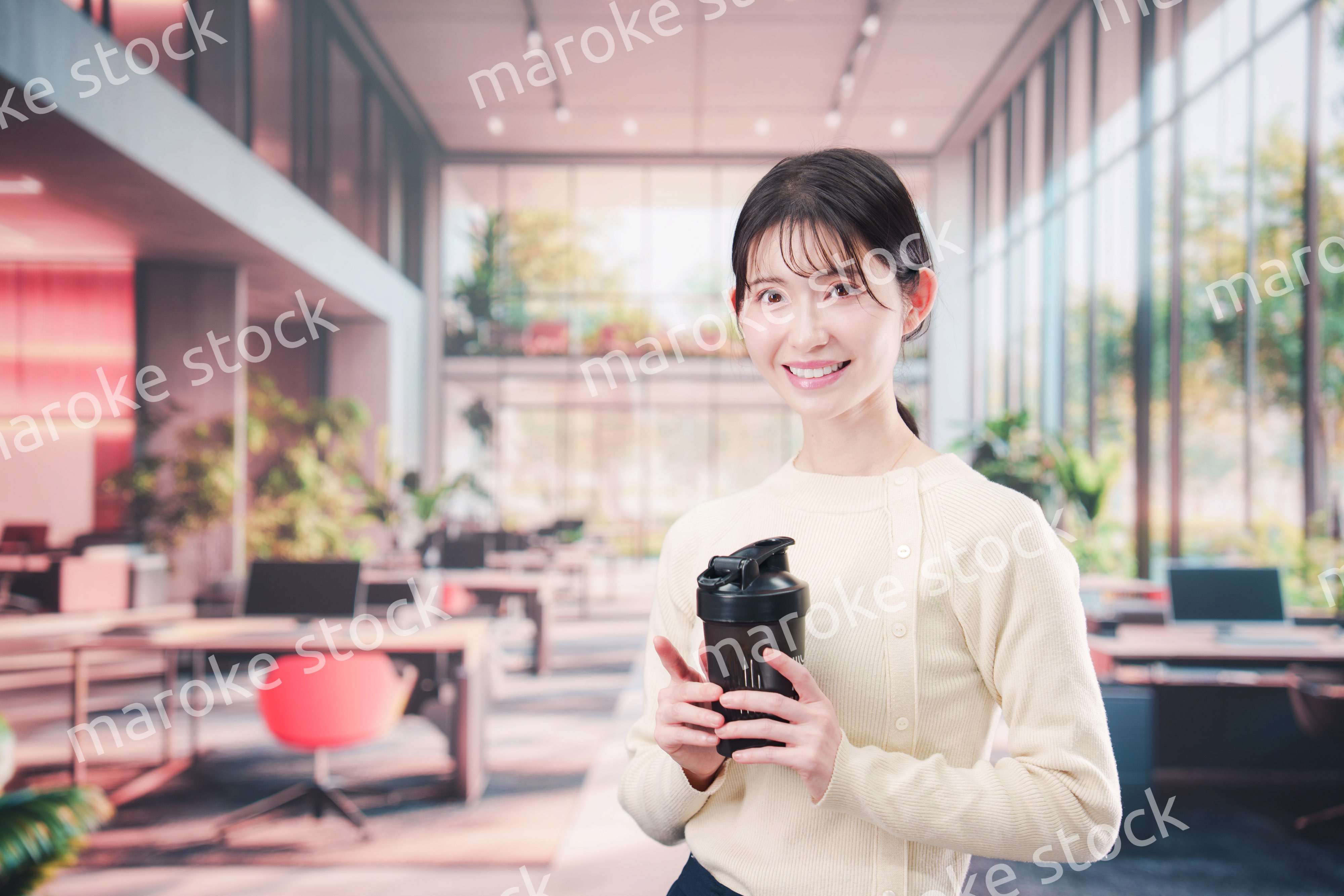 オフィスでマイボトルを持ち歩く若い女性