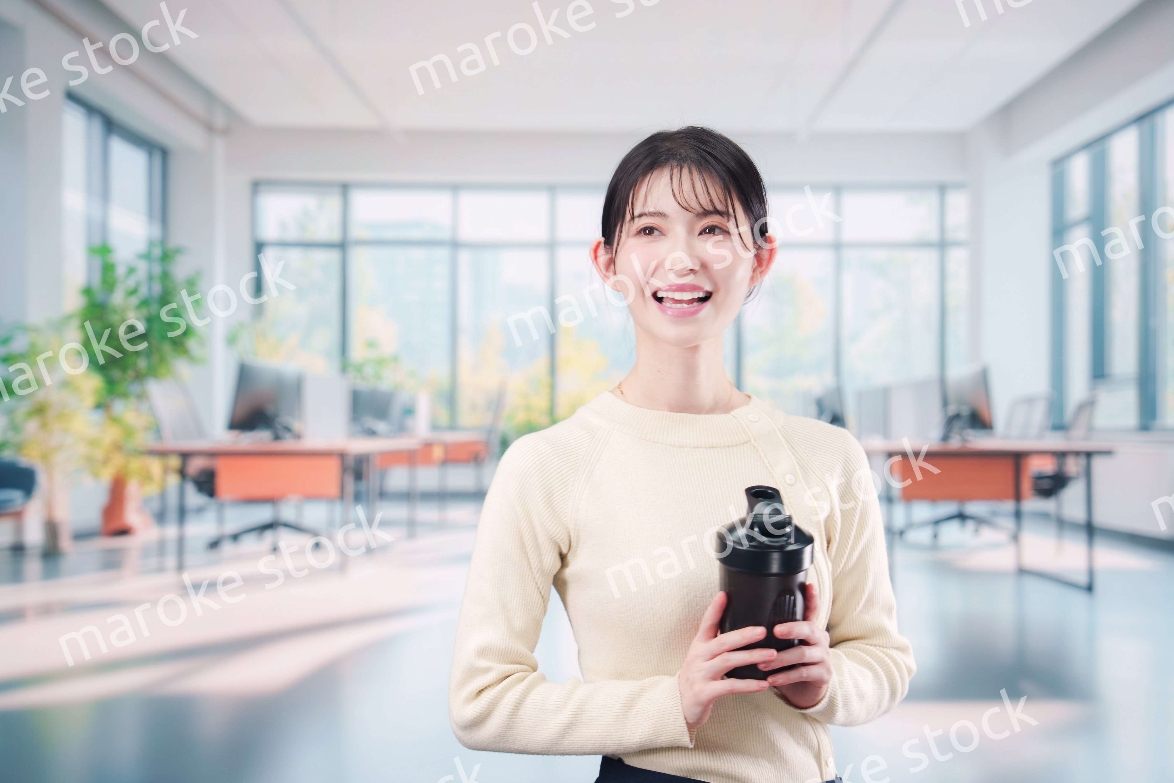 オフィスでマイボトルを持ち歩く若い女性