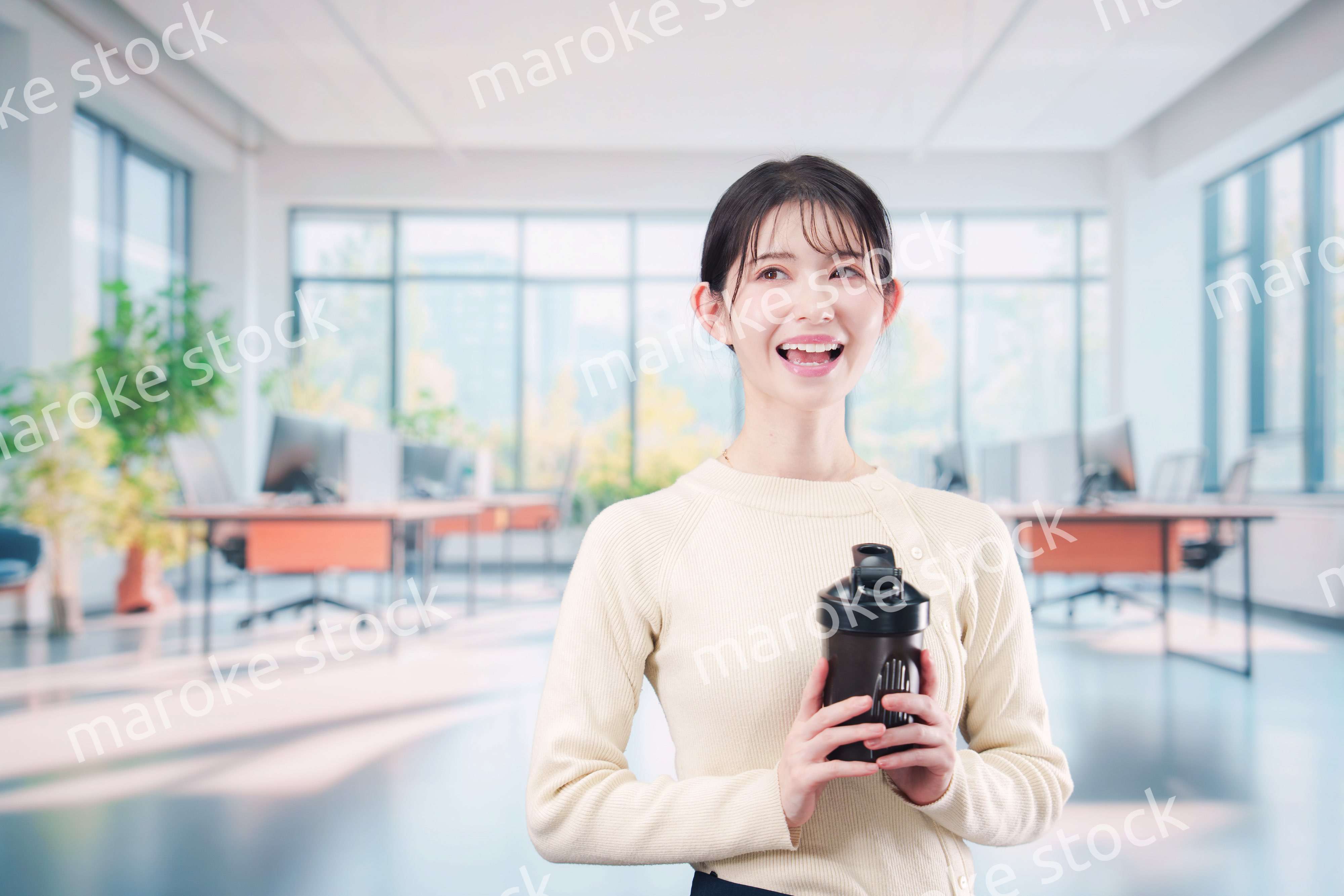 オフィスでマイボトルを持ち歩く若い女性