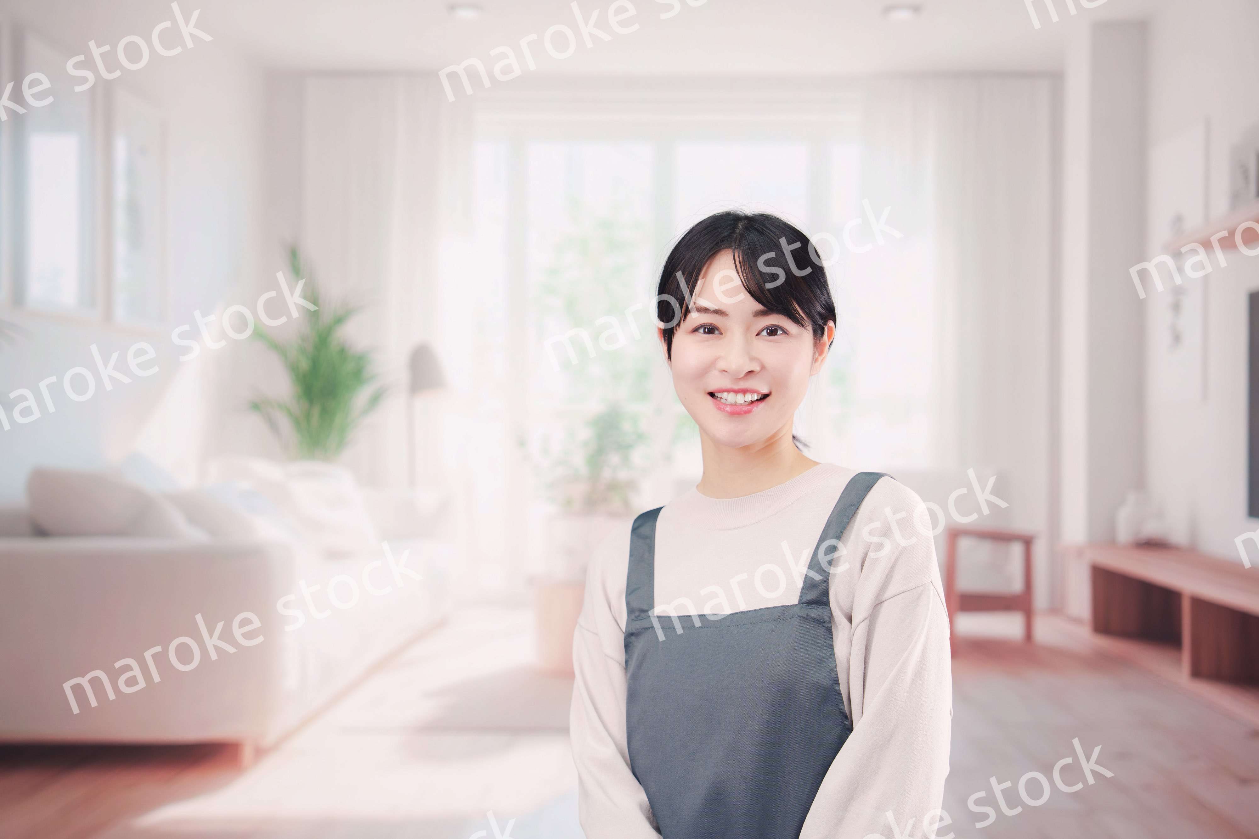 エプロンをしてお客様の家で働く家事代行の女性