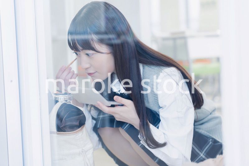 学校でメイクをする女子高生