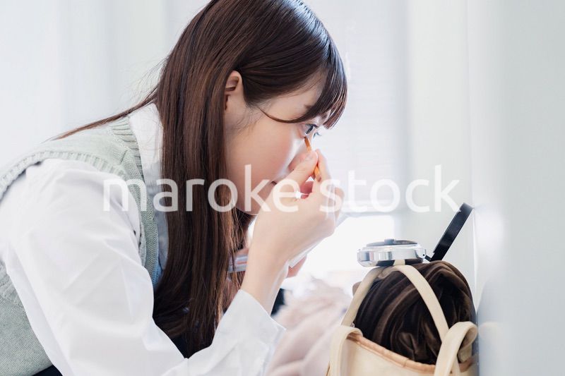 学校でメイクをする女子高生