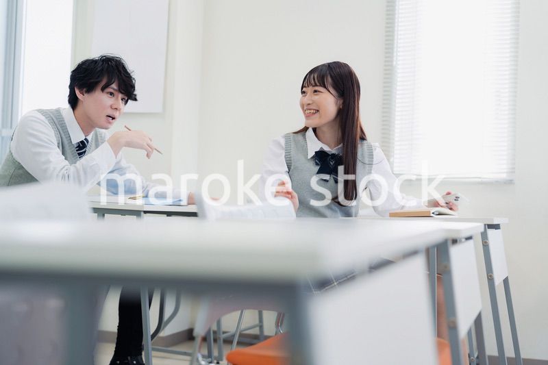同級生と教室で仲良く話す高校生