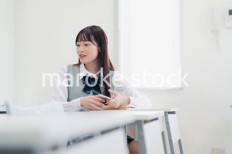 同級生と教室で仲良く話す高校生