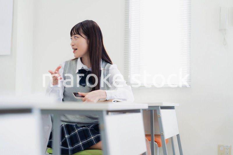 同級生と教室で仲良く話す高校生