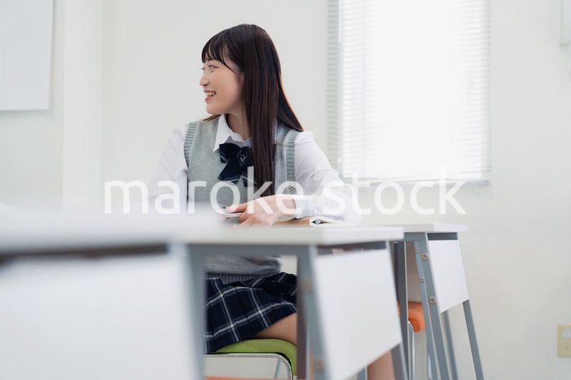 同級生と教室で仲良く話す高校生