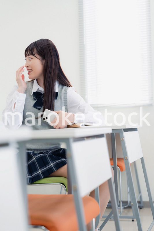 同級生と教室で仲良く話す高校生