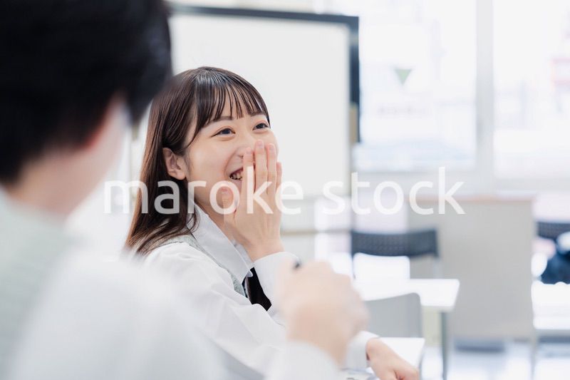 同級生と教室で仲良く話す高校生