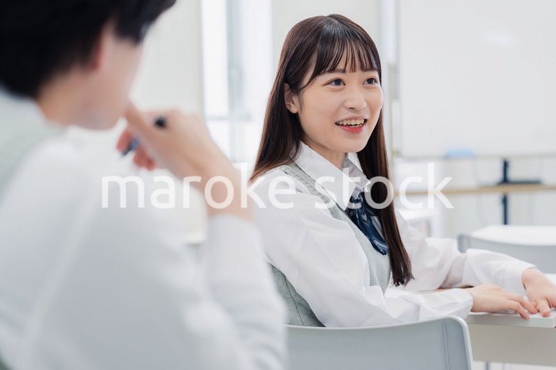 同級生と教室で仲良く話す高校生