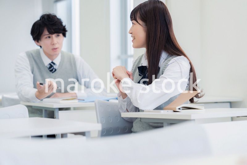 同級生と教室で仲良く話す高校生