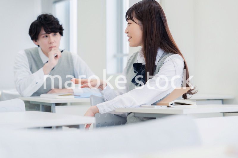 同級生と教室で仲良く話す高校生