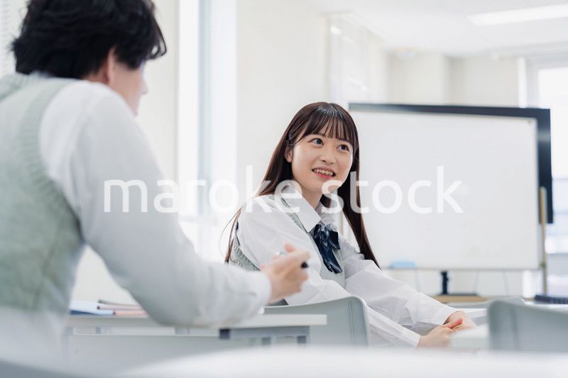 同級生と教室で仲良く話す高校生