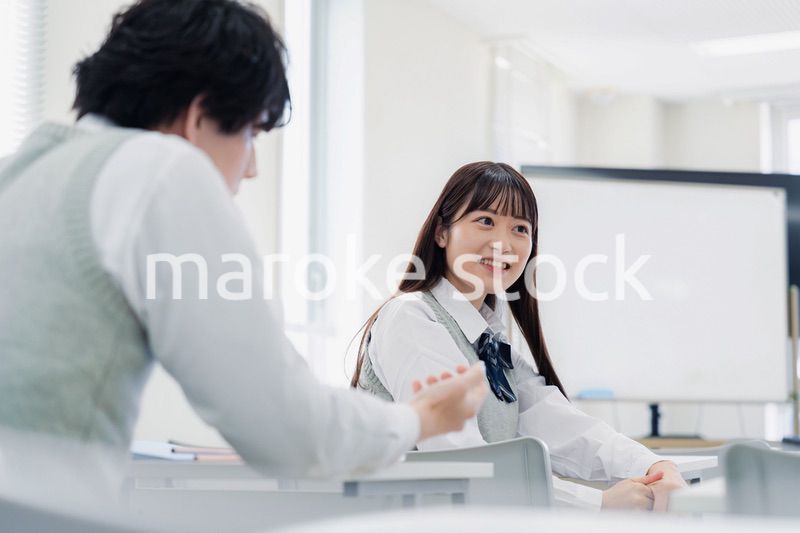 同級生と教室で仲良く話す高校生