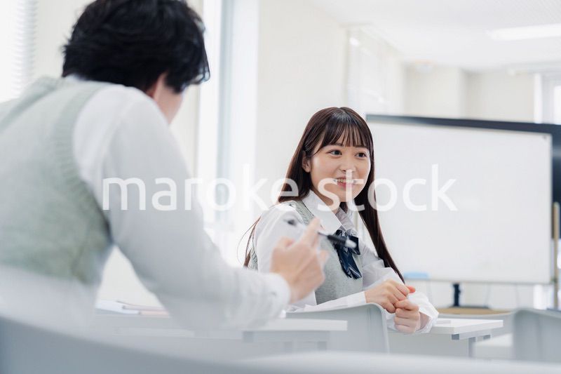 同級生と教室で仲良く話す高校生