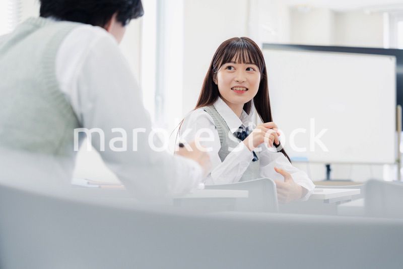 同級生と教室で仲良く話す高校生