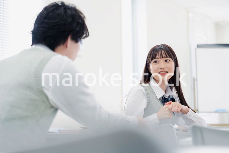 同級生と教室で仲良く話す高校生