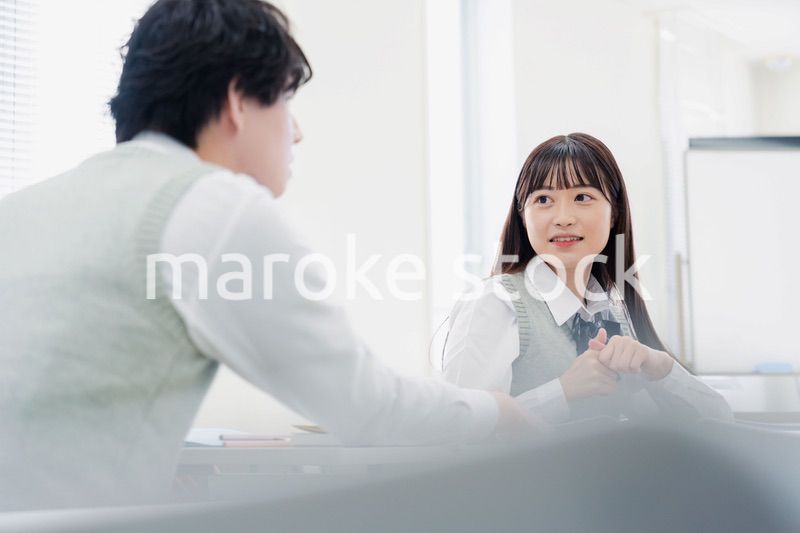 同級生と教室で仲良く話す高校生