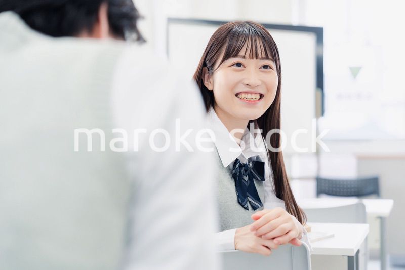 同級生と教室で仲良く話す高校生