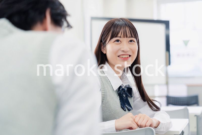 同級生と教室で仲良く話す高校生