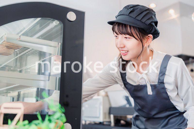 ショーケースに商品を並べる若い店員