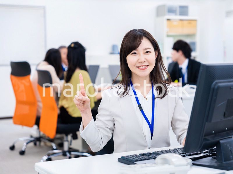 笑顔でポイントを指すビジネスウーマン