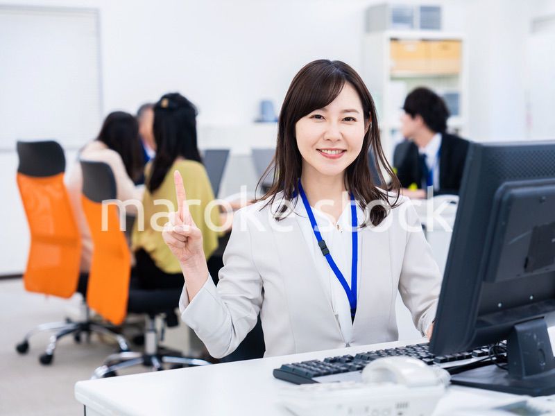 笑顔でポイントを指すビジネスウーマン