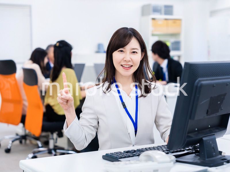 笑顔でポイントを指すビジネスウーマン