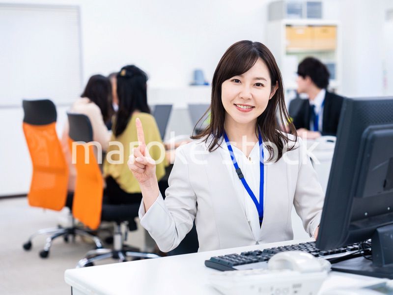 笑顔でポイントを指すビジネスウーマン