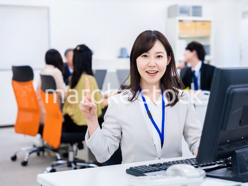 笑顔でポイントを指すビジネスウーマン