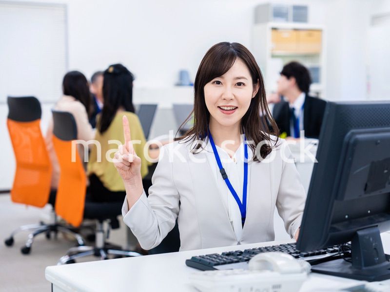 笑顔でポイントを指すビジネスウーマン