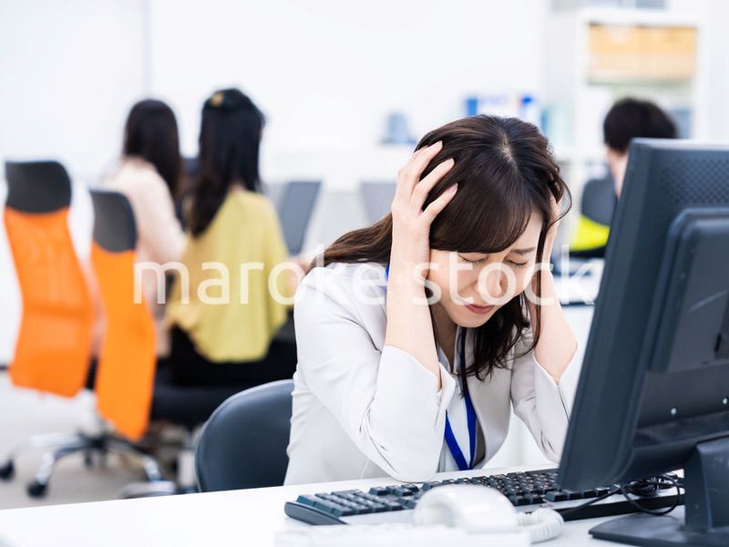 デスクワークをしながら頭を抱えるビジネスウーマン