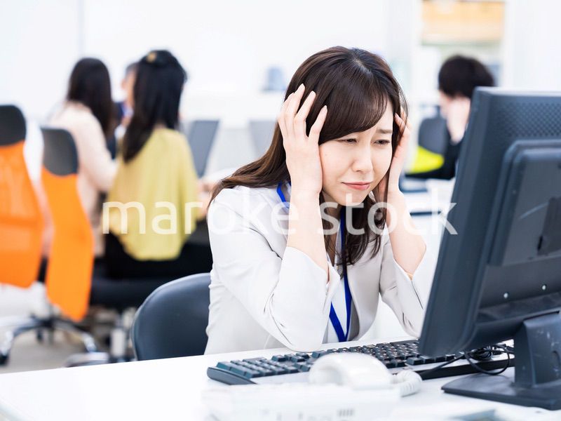 デスクワークをしながら頭を抱えるビジネスウーマン