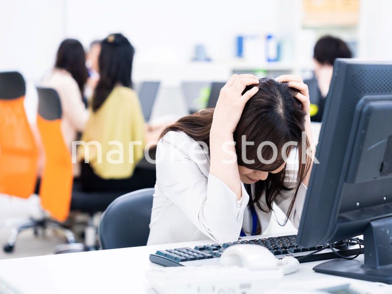 デスクワークをしながら頭を抱えるビジネスウーマン