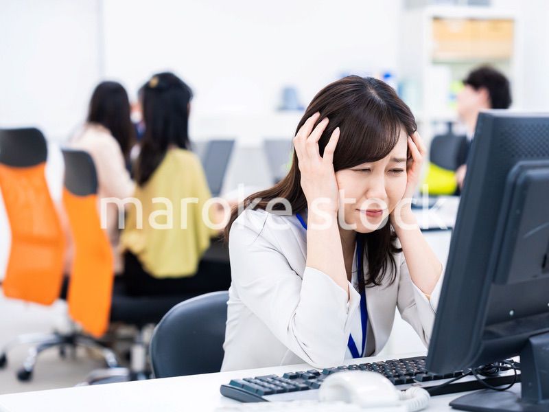 デスクワークをしながら頭を抱えるビジネスウーマン