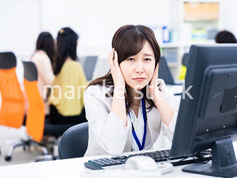 デスクワークをしながら頭を抱えるビジネスウーマン