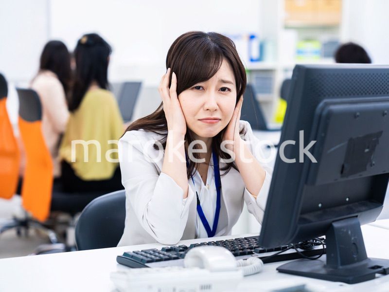 デスクワークをしながら頭を抱えるビジネスウーマン