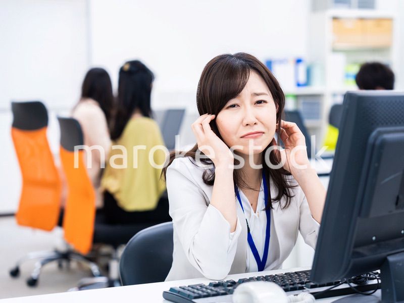 デスクワークをしながら頭を抱えるビジネスウーマン
