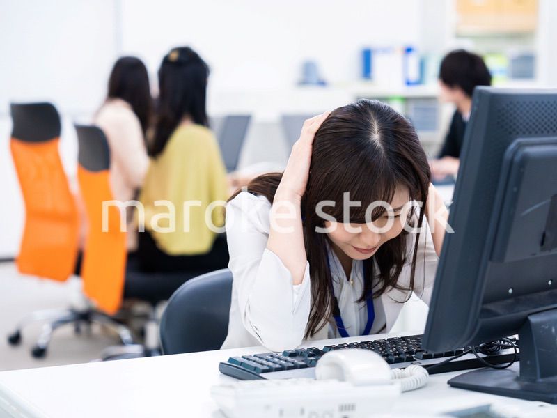 デスクワークをしながら頭を抱えるビジネスウーマン