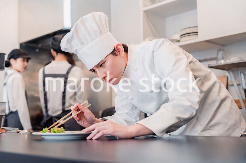 厨房で盛り付けをする男性シェフ