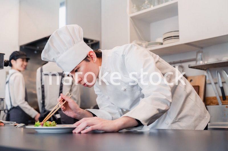 厨房で盛り付けをする男性シェフ