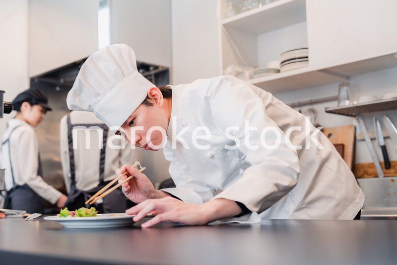 厨房で盛り付けをする男性シェフ