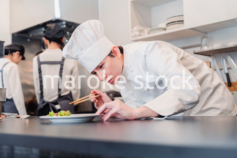 厨房で盛り付けをする男性シェフ