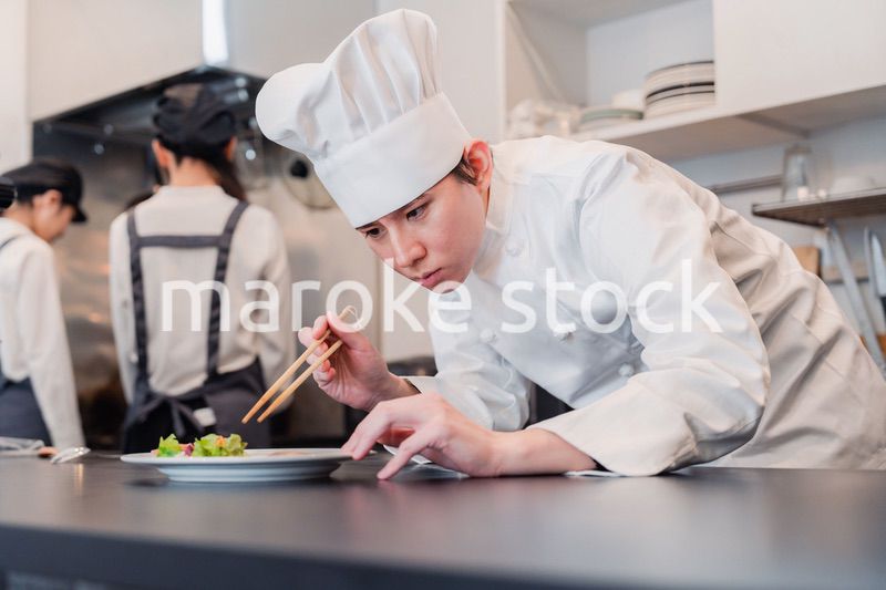 厨房で盛り付けをする男性シェフ