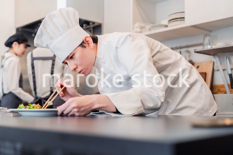 厨房で盛り付けをする男性シェフ