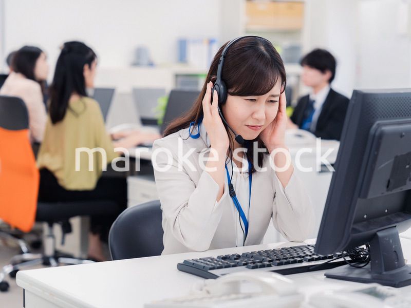 電話対応で疲労するお客様センターの女性