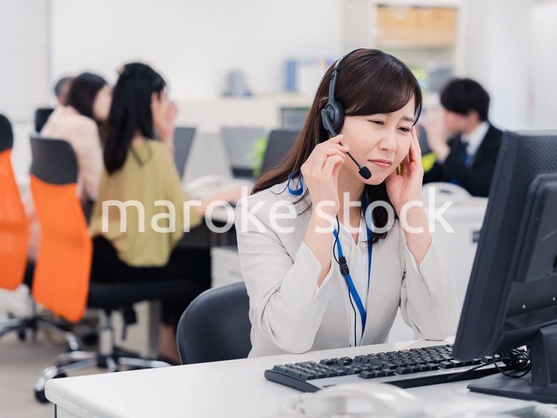 電話対応で疲労するお客様センターの女性