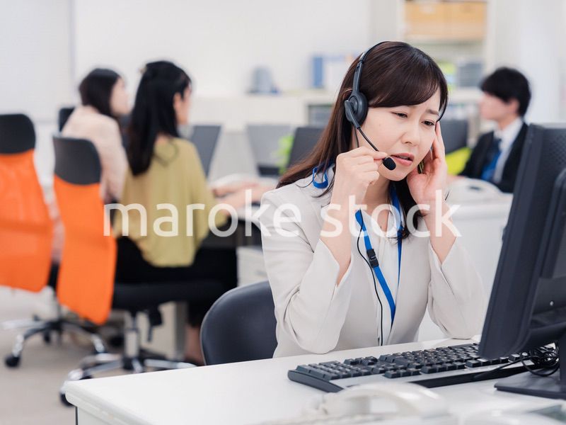 電話対応で疲労するお客様センターの女性