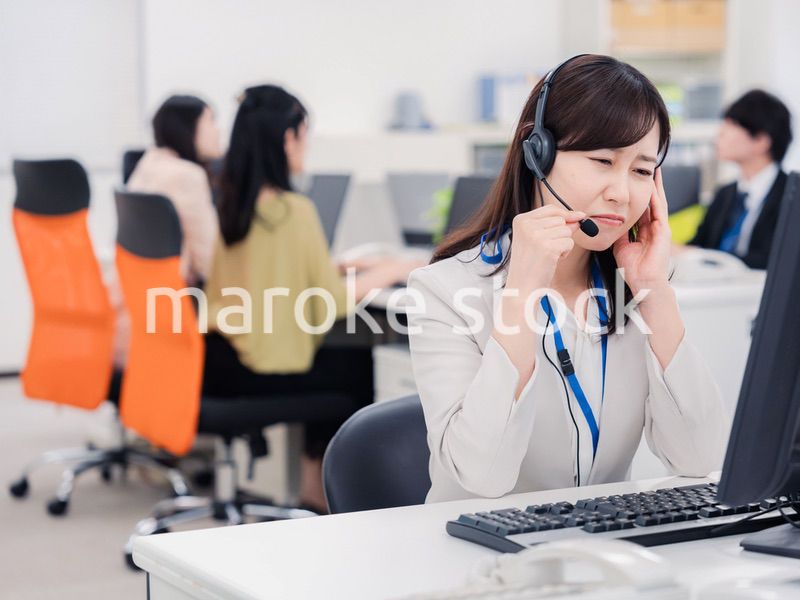 電話対応で疲労するお客様センターの女性
