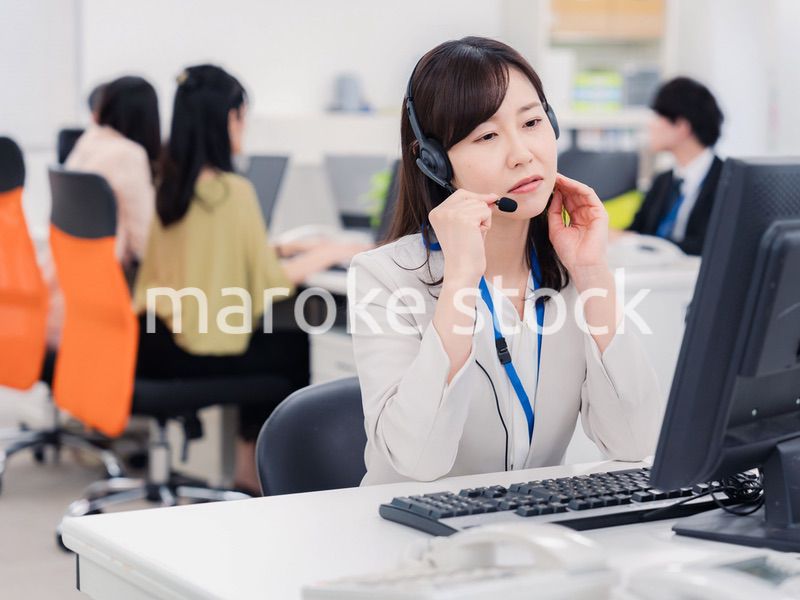 電話対応で疲労するお客様センターの女性